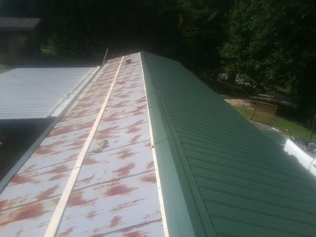 Old rusted panels beside newly installed green metal roofing — Wind Damage Roof Repair by Roofing Brothers in New Vienna