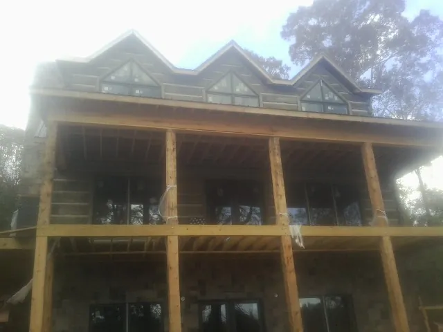 Dormers and porch framing on a large log home under construction — Roof Coating work by our crew in New Vienna