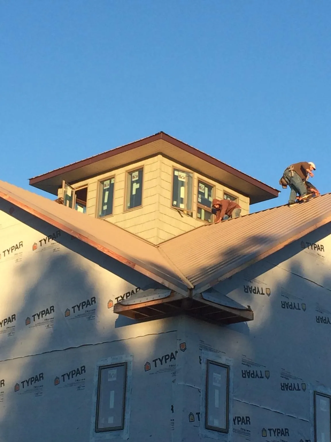 Roofers working around a rooftop cupola on a new metal roof at sunset — Roof Waterproofing in New Vienna by Roofing Brothers
